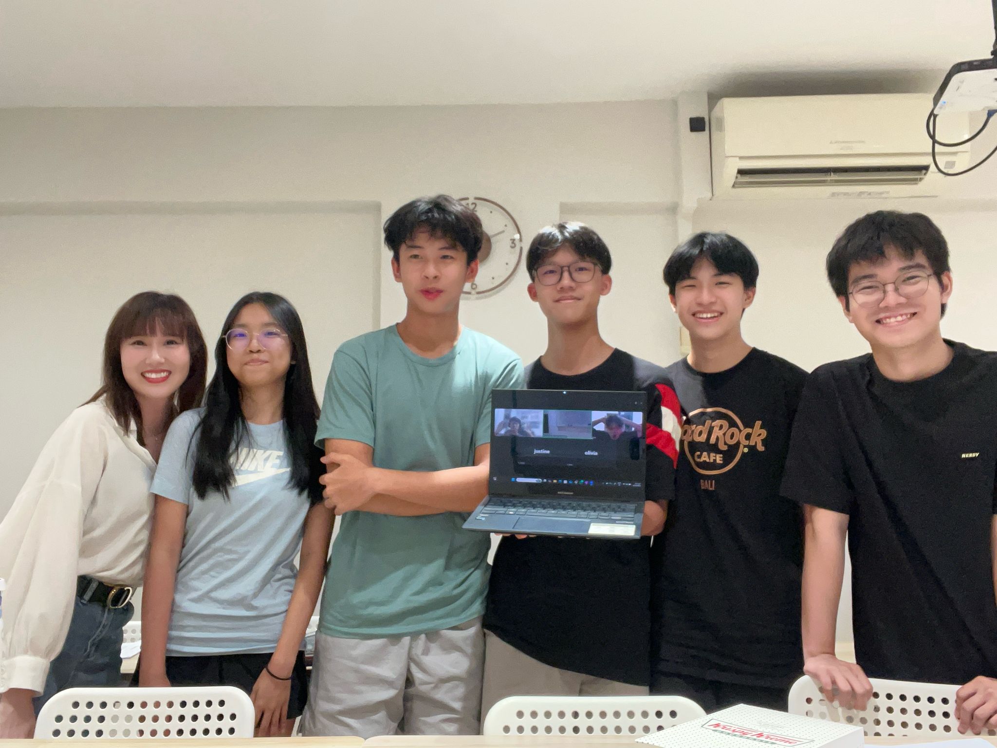 Smiling students posing with a laptop.