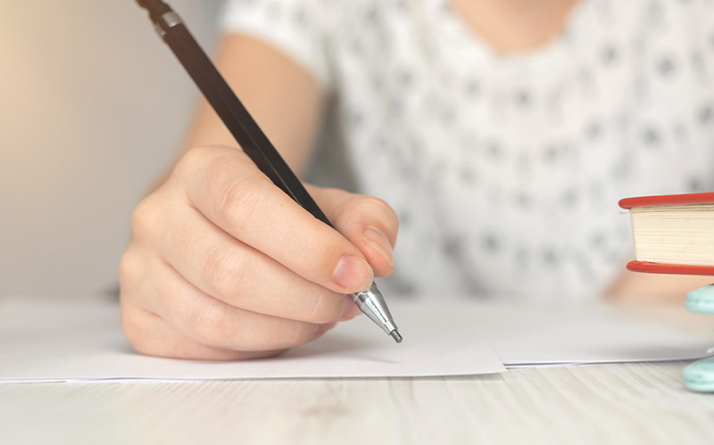 Student writing an essay with a mechanical pencil.
