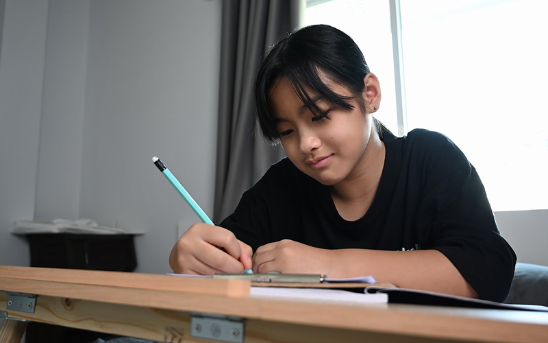 Secondary student practicing English essay writing with a pencil.