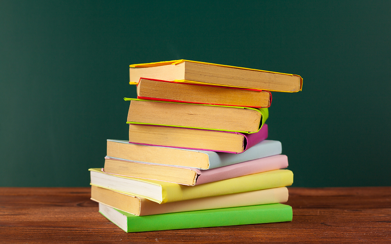 Stack of colorful textbooks for General Paper exam revision.